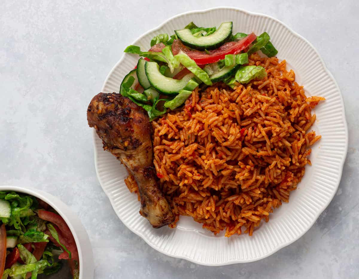 Jollof rice, chicken and salad plated for a home meal